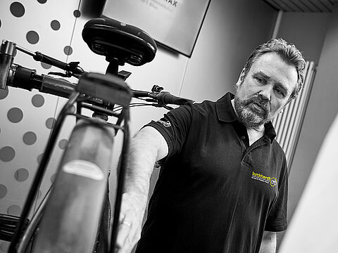 Fahrradmonteur steht neben Fahrrad